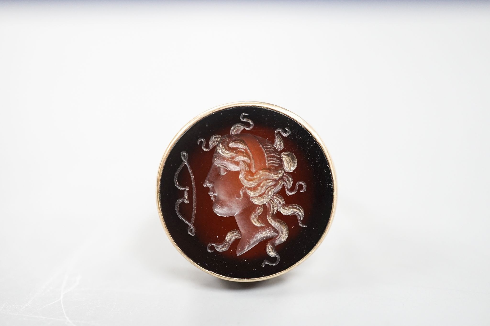 An early 20th century 9ct and intaglio brown chalcedony set ring, carved with the bust of a lady to dexter, size Q, gross weight 8.4 grams.